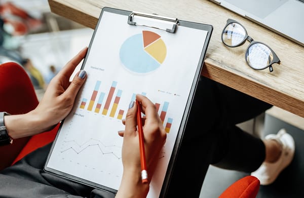 Person holding a clipboard with business charts and graphs.