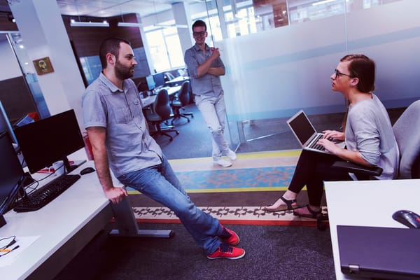 Three people engaged in a discussion in a modern office setting.