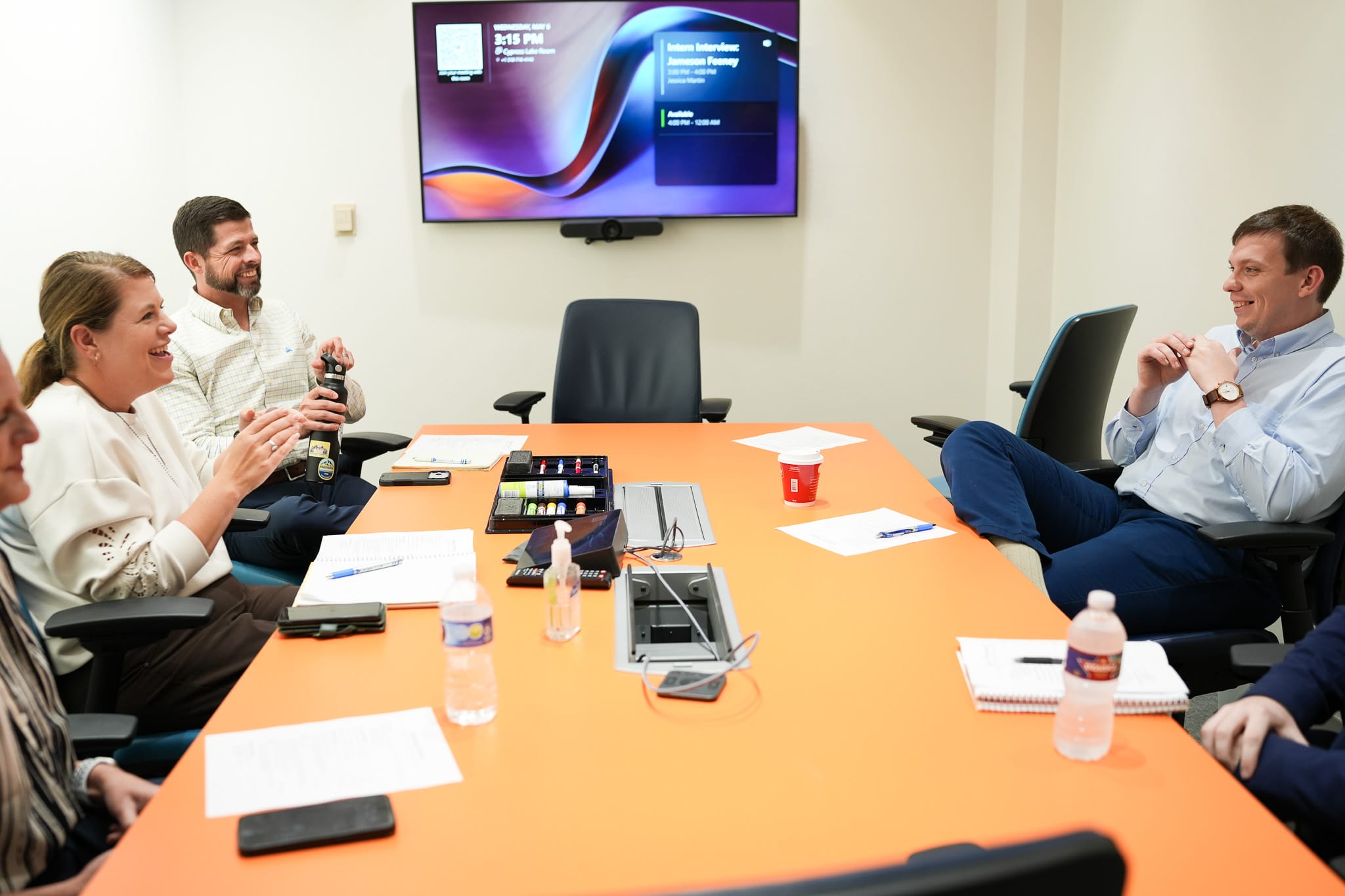 Four people engaged in a casual team meeting in a conference room
