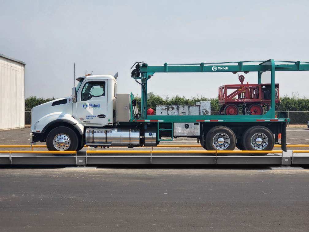 White Michelli truck with crane positioned on an industrial truck scale
