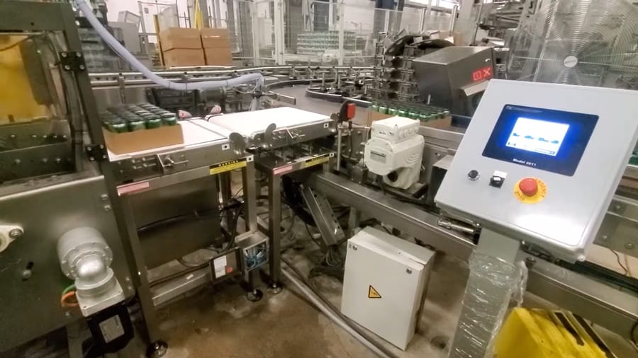 Automated production line with conveyor belt and control panel touchscreen in a factory