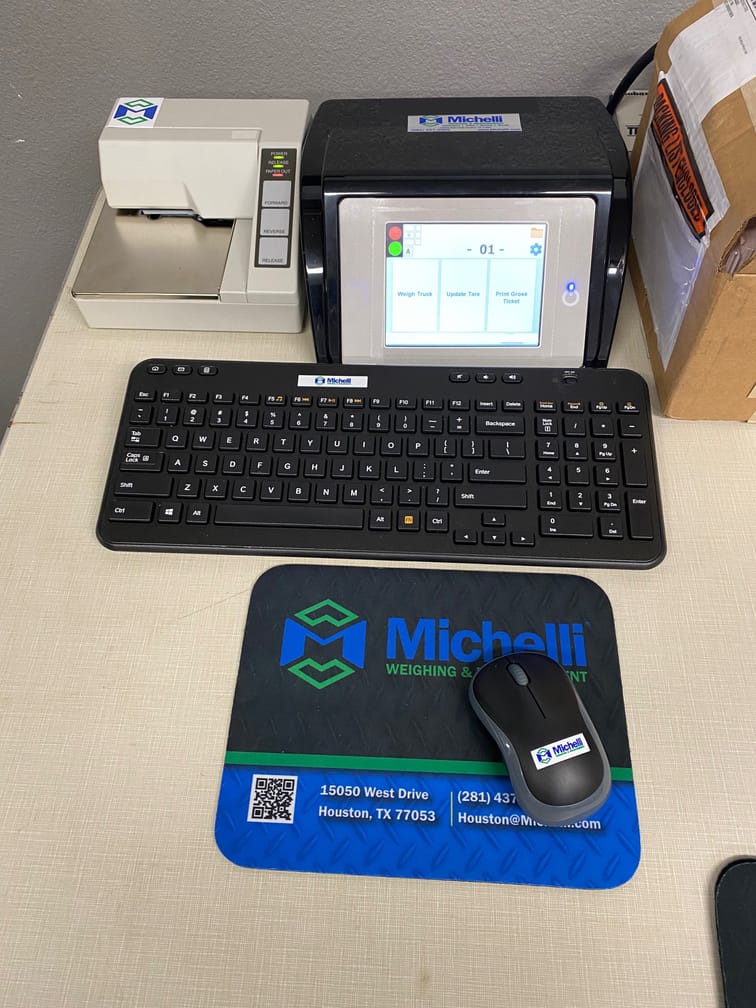 Office desk with keyboard, weighing display, and Michelli-branded mouse pad for integrated truck scale system