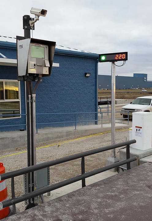 Security camera and digital weight display mounted outside a blue industrial truck scale facility