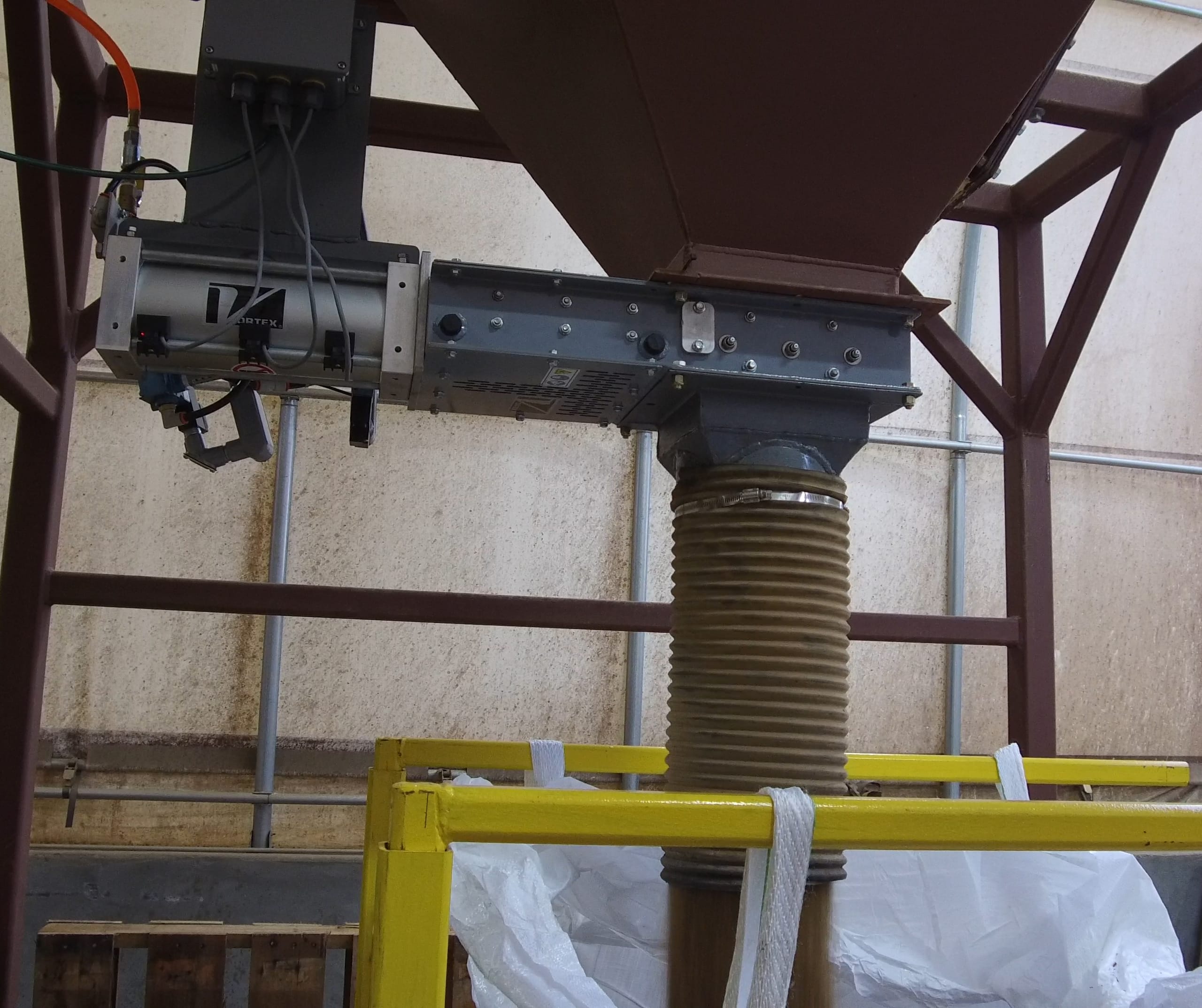 Industrial hopper with a chute connected to a fabric bag below