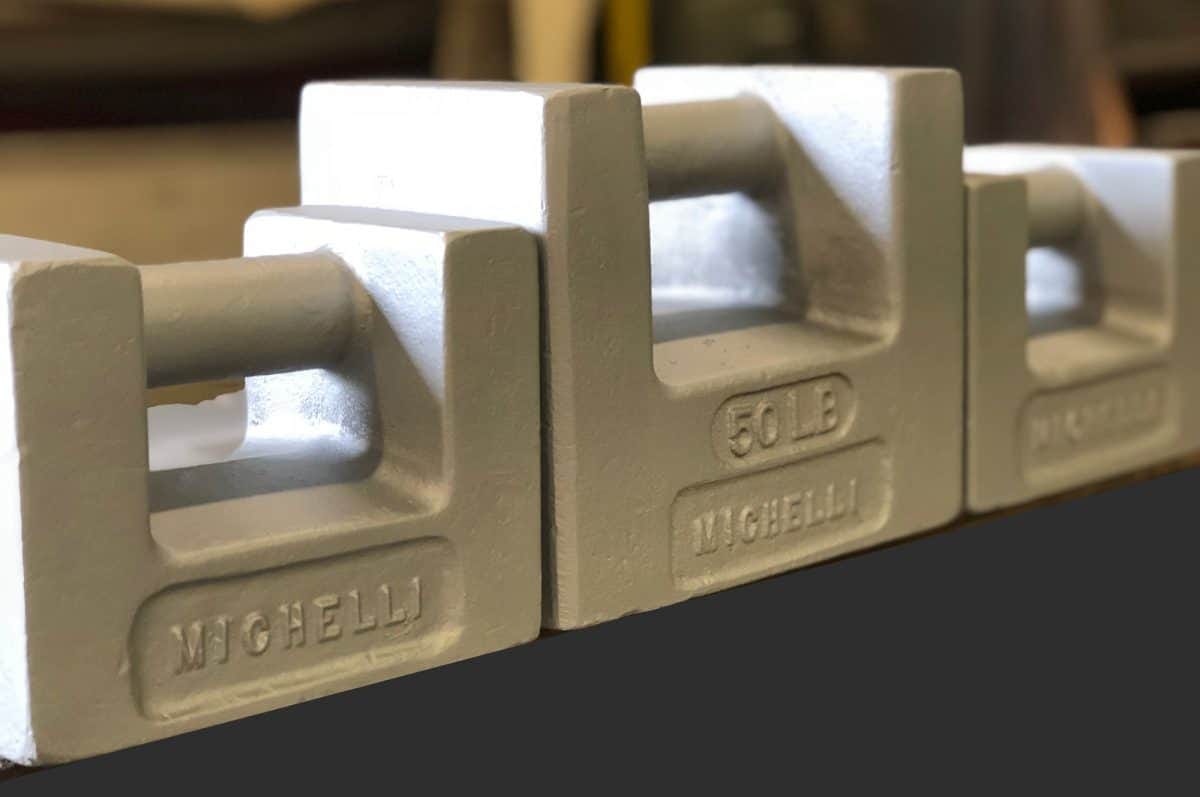 Stainless steel calibration test weights arranged on a surface for scale calibration service