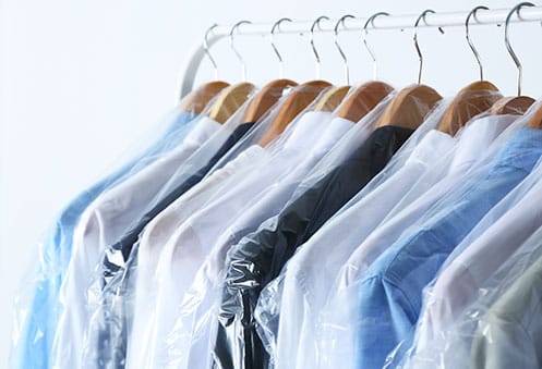 Freshly dry-cleaned garments hanging in protective covers
