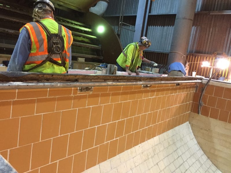 Workers installing tile lining inside an industrial tank