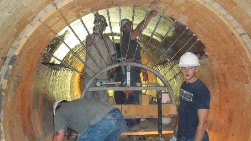 Workers installing refractory brick inside a kiln