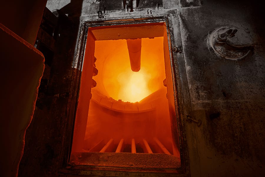 An industrial furnace glowing bright orange through its open door