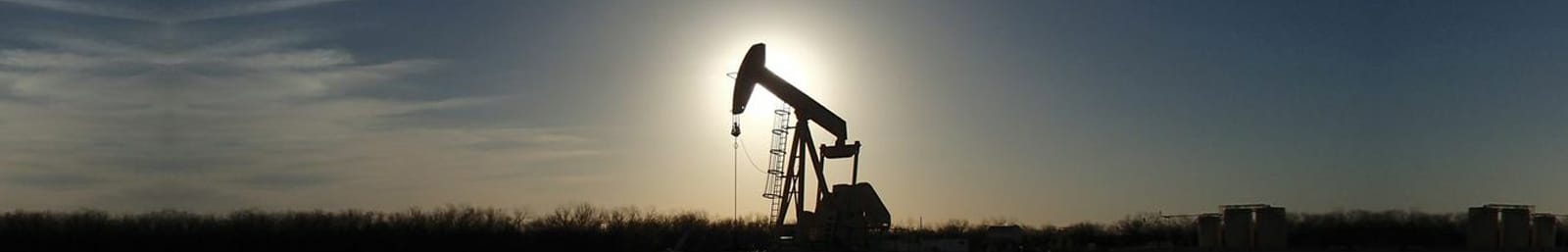 Pumpjack at sunset over open land